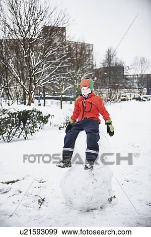 Boy sitting on snowman in park View Large Photo Image Stock Photo - Boy sitting on snowman in park. Fotosearch
