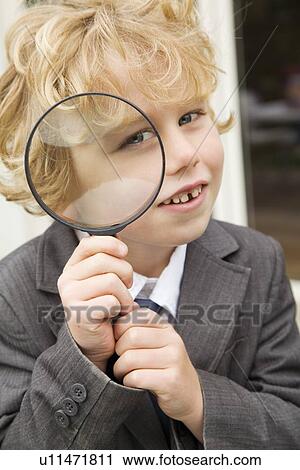 Stock Image - Boy using magnifying glass outdoors. Fotosearch