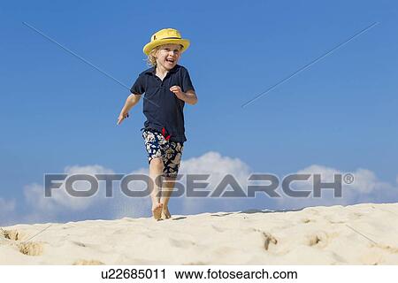 Boy walking on sandy beach View Large Photo Image Stock Image - Boy walking on sandy beach. Fotosearch