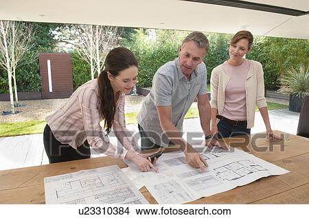 Picture - Business people reading blueprints. Fotosearch