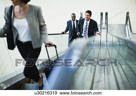 Business people riding escalator View Large Photo Image Stock Photo - Business people riding escalator. Fotosearch