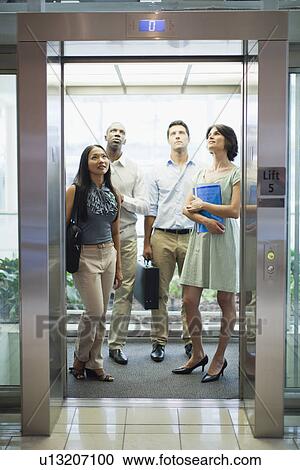 Stock Image - Business people riding glass elevator. Fotosearch