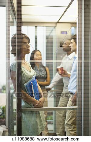 Stock Photo - Business people riding glass elevator. Fotosearch