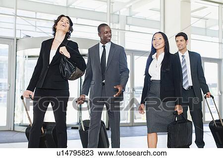 Business people rolling luggage in lobby View Large Photo Image Stock Image - Business people rolling luggage in lobby. Fotosearch