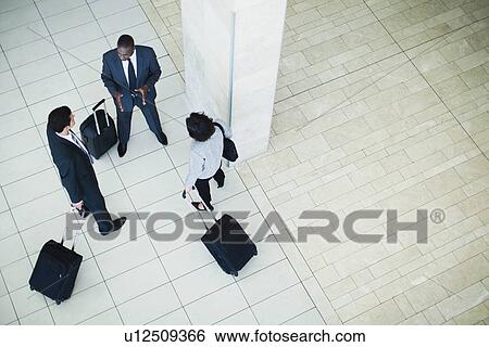 Business people rolling luggage in lobby View Large Photo Image Stock Photograph - Business people rolling luggage in lobby. Fotosearch
