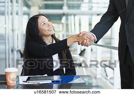 Stock Photo - Business people shaking hands in cafe. Fotosearch
