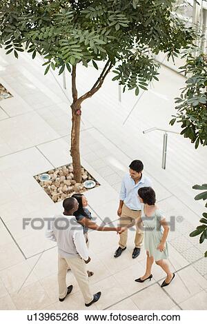 Stock Photo - Business people shaking hands in lobby. Fotosearch