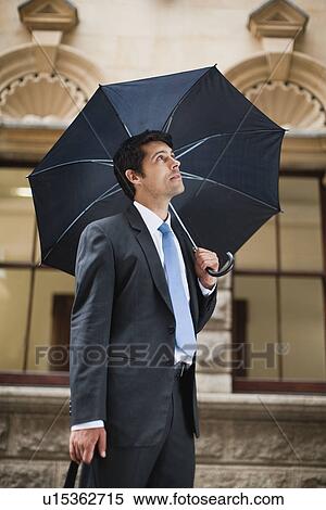 Stock Photography - Businessman carrying umbrella on street. Fotosearch