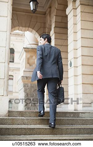 Stock Image - Businessman climbing steps of building. Fotosearch
