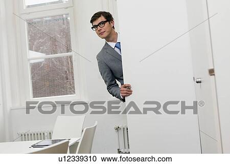 Businessman peering around door View Large Photo Image Stock Image - Businessman peering around door. Fotosearch