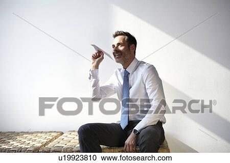Stock Image - Businessman playing with paper airplane. Fotosearch
