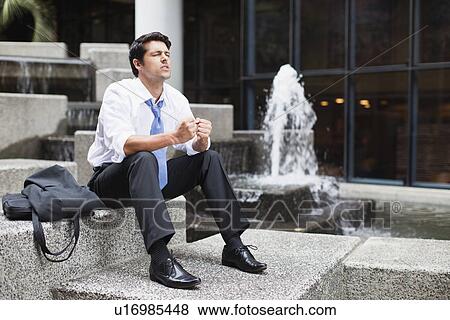 Businessman sitting on urban fountain View Large Photo Image Stock Photo - Businessman sitting on urban fountain. Fotosearch
