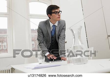 Businessman standing at desk View Large Photo Image Stock Photograph - Businessman standing at desk. Fotosearch