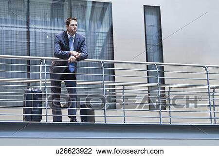 Stock Image - Businessman standing on balcony. Fotosearch