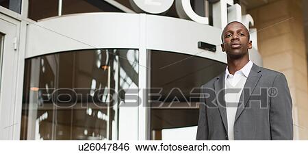 Businessman standing outside building View Large Photo Image Stock Photograph - Businessman standing outside building. Fotosearch