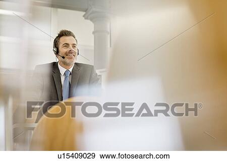 Stock Photo - Businessman wearing headset at podium. Fotosearch
