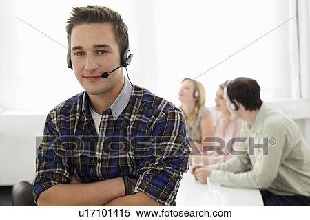 Stock Photography - Businessman wearing headset in meeting. Fotosearch