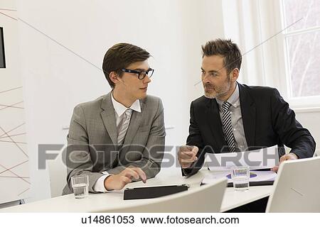 Stock Image - Businessmen talking in office. Fotosearch