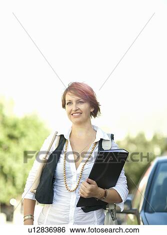 Businesswoman carrying folder outdoors View Large Photo Image Stock Photograph - Businesswoman carrying folder outdoors. Fotosearch