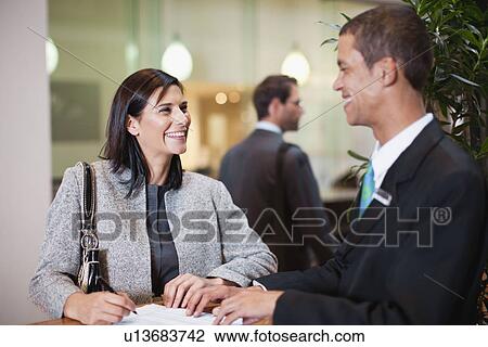 Stock Image - Businesswoman checking into hotel. Fotosearch