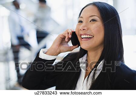 Stock Image - Businesswoman on cell phone in office. Fotosearch