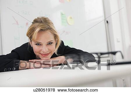 Businesswoman resting chin on desk View Large Photo Image Stock Photo - Businesswoman resting chin on desk. Fotosearch