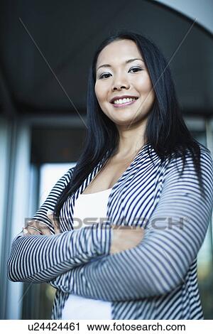 Stock Image - Businesswoman standing with arms folded. Fotosearch