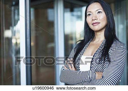 Stock Photograph - Businesswoman standing with arms folded. Fotosearch