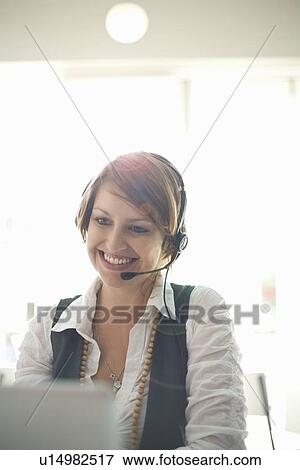 Stock Photo - Businesswoman wearing headset at desk. Fotosearch
