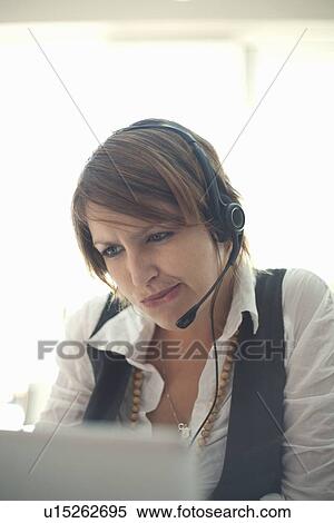 Stock Photography - Businesswoman wearing headset at desk. Fotosearch