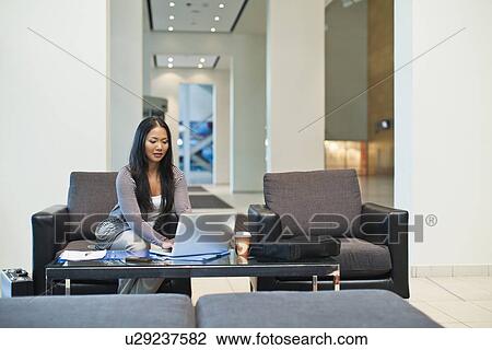 Stock Image - Businesswoman working in lobby. Fotosearch