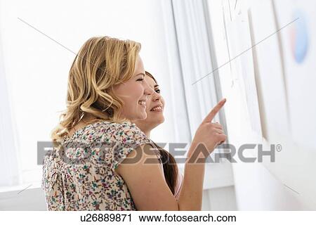 Stock Image - Businesswomen reading signs in office. Fotosearch