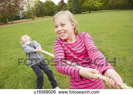 Stock Photograph - Children playing tug-of-war outdoors. Fotosearch