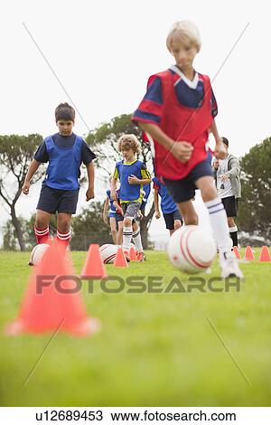 Stock Image - Childrens soccer team training on pitch. Fotosearch