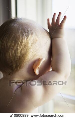 Stock Photo - Close up of baby girl at window. Fotosearch