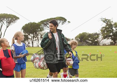 Coach carrying soccer balls on pitch View Large Photo Image Picture - Coach carrying soccer balls on pitch. Fotosearch