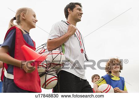 Coach carrying soccer balls on pitch View Large Photo Image Stock Image - Coach carrying soccer balls on pitch. Fotosearch