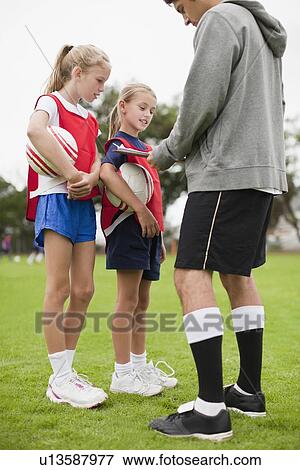 Stock Photo - Coach talking to children on soccer team. Fotosearch