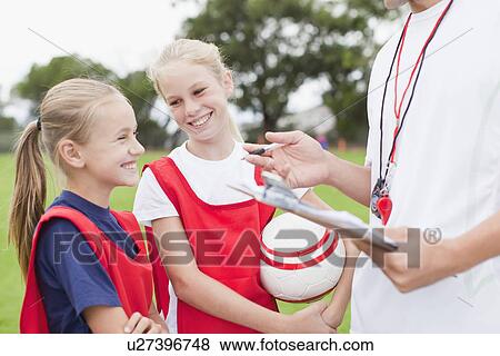 Stock Photo - Coach talking to children on soccer team. Fotosearch