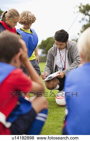 Stock Photo - Coach talking to childrens soccer team. Fotosearch