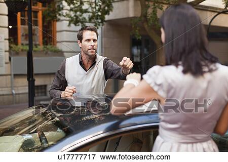 Stock Photo - Couple arguing over sports car. Fotosearch