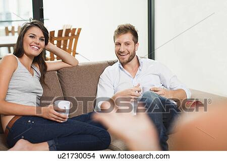 Picture - Couple having coffee together on sofa. Fotosearch