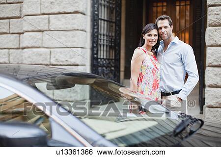 Stock Photograph - Couple hugging by car on city street. Fotosearch