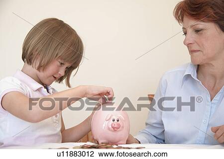 Daughter putting money in piggy bank View Large Photo Image Stock Image - Daughter putting money in piggy bank. Fotosearch