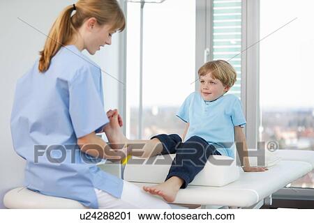 Stock Image - Doctor examining boys feet in office. Fotosearch