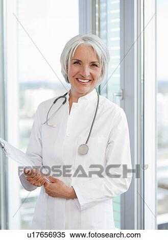Stock Photography - Doctor holding clipboard in hospital. Fotosearch