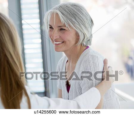 Doctor hugging smiling woman in office View Large Photo Image Stock Image - Doctor hugging smiling woman in office. Fotosearch