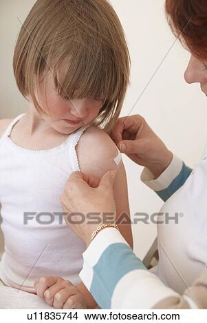 Doctor placing bandage on girls shot View Large Photo Image Picture - Doctor placing bandage on girls shot. Fotosearch