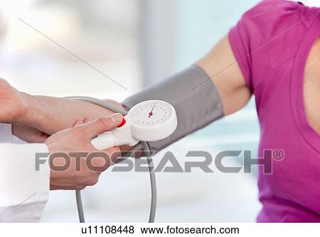 Stock Photo - Doctor taking womans blood pressure. Fotosearch