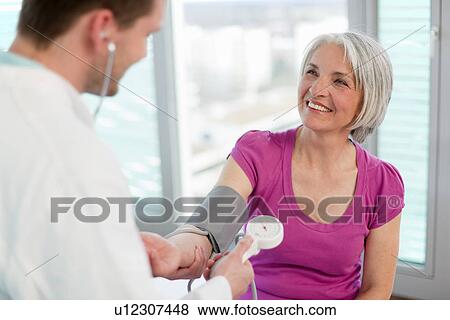 Stock Photo - Doctor taking womans blood pressure. Fotosearch